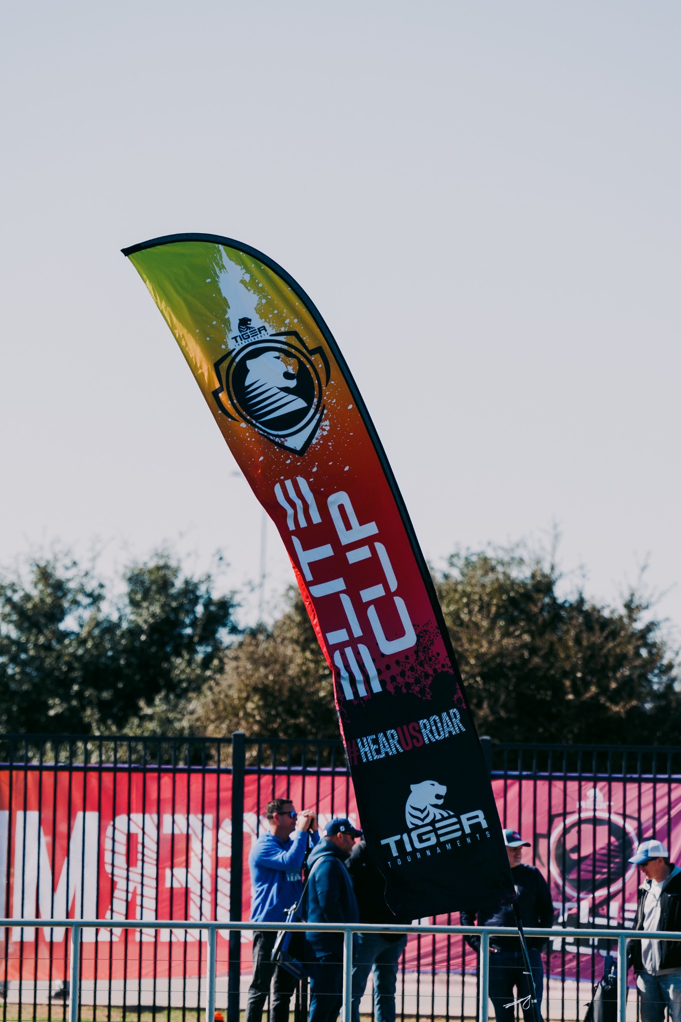 Elite Cup feather flag installed alongside tournament field fencing