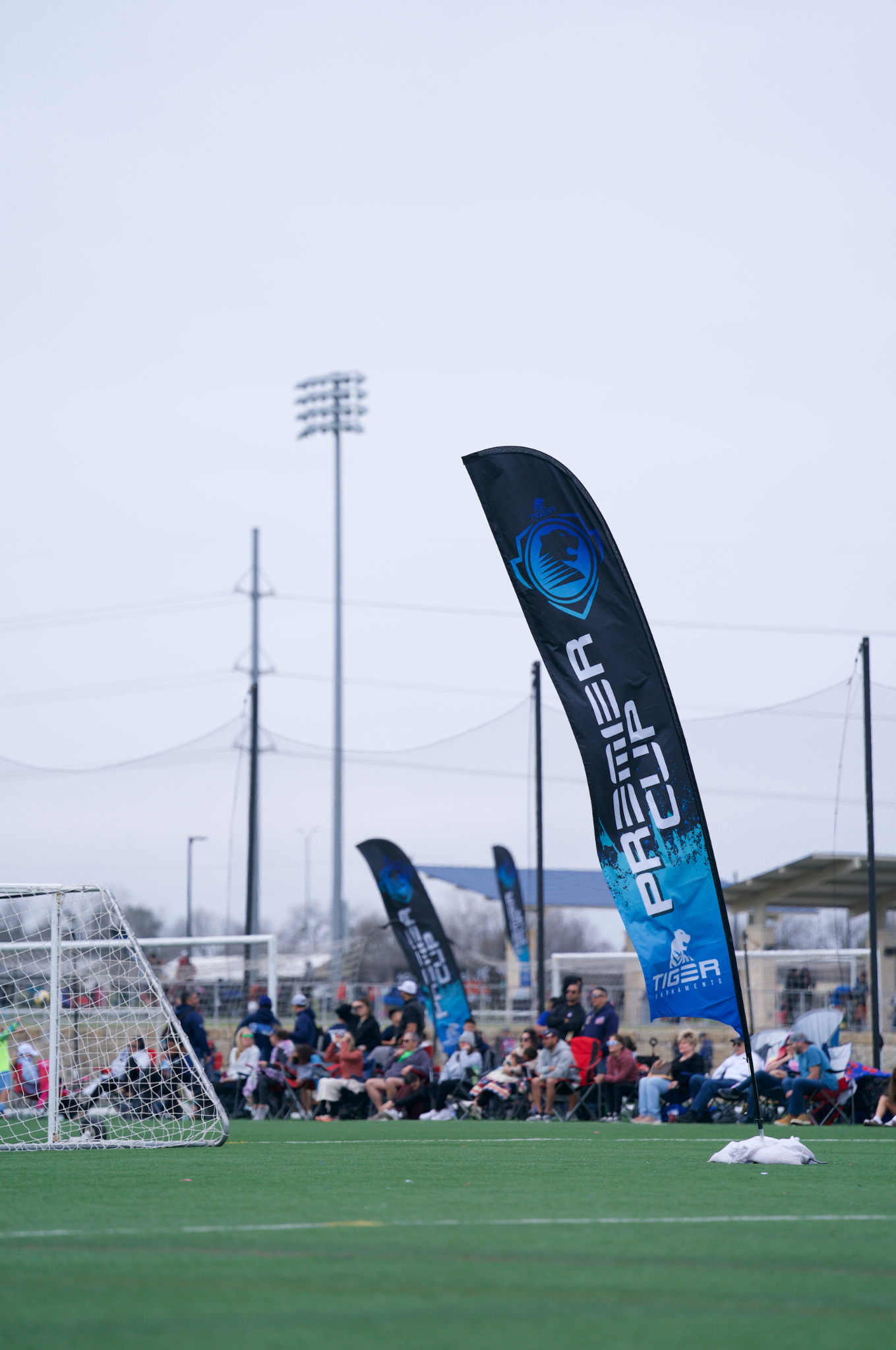 Blue Premier Cup feather flags along the sideline of a soccer tournament